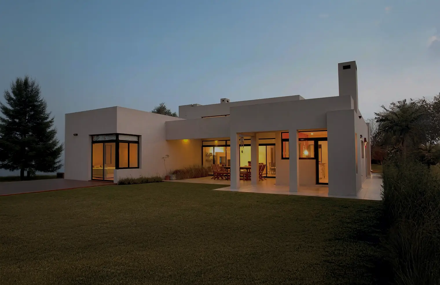 Casa de una planta con galería y jardín al atardecer